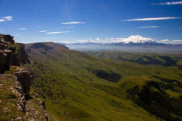 An excellent view from the plateau to the extinct volcano and the snowy peak of Mount Elbrus. Below is a green gorge