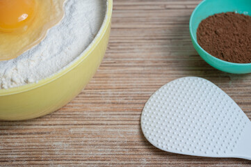 bowls of flour, egg and cocoa are on the kitchen table