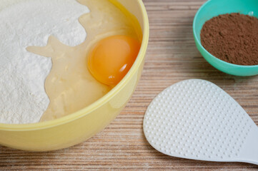 bowls of flour, egg and cocoa are on the kitchen table