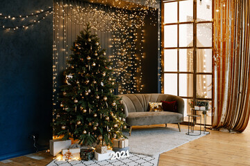 Christmas tree in the interior of the living room, decorated with gifts and garlands. Stylish interior in dark and gold tones, decorated for the New Year.