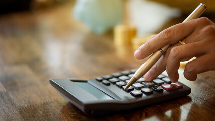 A business woman holding a pen and pressing a calculator to calculate the pattern