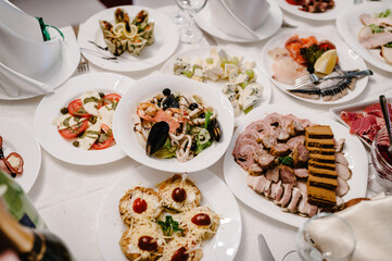 Serves dinner on a festive table. Food, Salads, Meat, Fish Meals. Festive table at the wedding banquet. Decor. Details.