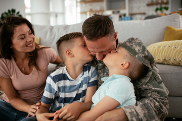 Happy soldier sitting on the floor with his family. Soldier and his wife enjoying at home with children.