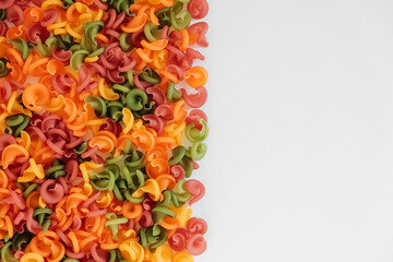 Multicolored pasta scattered on a white background. Top view. Copy, empty space for text