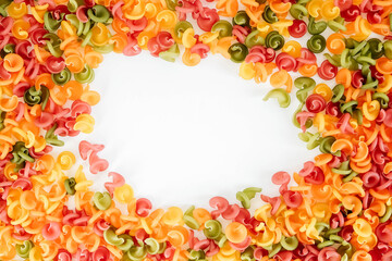 Multicolored pasta scattered on a white background in the form of a frame. Top view. Copy, empty space for text