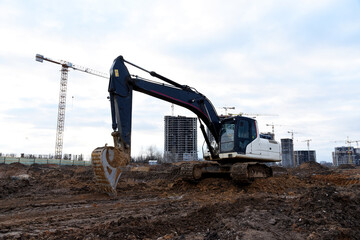 Excavator during earthmoving at construction site. Backhoe dig ground for the construction of foundation and laying sewer pipes district heating. Earth-moving heavy equipment on road works