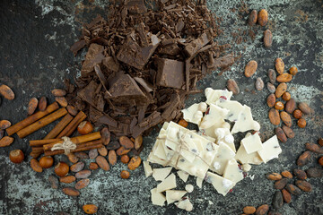Pieces of dark chocolate and cocoa beans in composition on old background