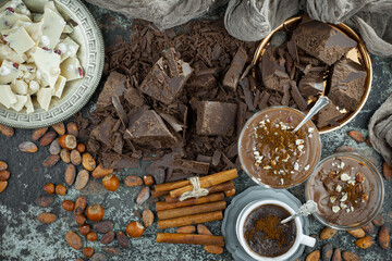 Pieces of dark chocolate and cocoa beans in composition on old background