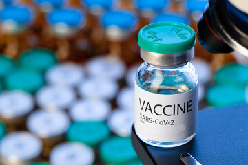 Vial of Covid-19 vaccine next to a microscope