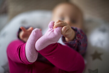 Baby lying back holding its foot
