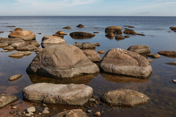 Fototapeta na wymiar Granite stones on the beach of the Gulf of Finland in bright summer day