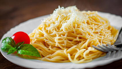 spaghetti pasta with grated cheese in white plate on wooden table