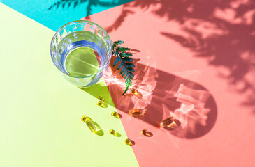 Glass of clear transparent water on a colorful background in natural light with harsh shadows.