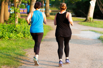 Two women on a dirt path running around a lake in the woods