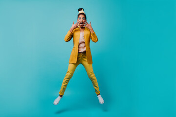 Magnificent girl jumping with surprised smile. Merry african woman dancing on blue background.