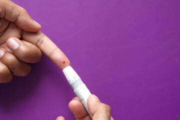 young man's hand measure glucose level at home 
