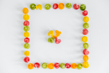 Multicolored pasta in the shape of a square on a white background. Top view. Copy, empty space for text