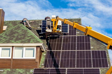 Workers installing solar panels on private home hexagonal roof felt on sunny day, blue sky. Real life. Home power plant.