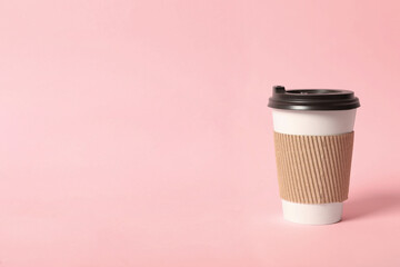 Takeaway paper coffee cup with cardboard sleeve on pink background. Space for text