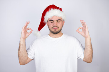 Young handsome man wearing a Santa hat over white background relax and smiling with eyes closed...