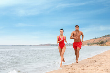 Professional lifeguards running at sandy beach on sunny day - Powered by Adobe