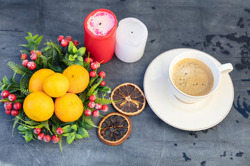coffee mug against black table background, tangerines, dried orange, cinnamon and accessories for winter holidays. New Year