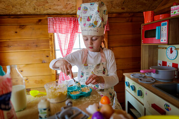 Young girl in wendy house pretending to cook in kitchen
