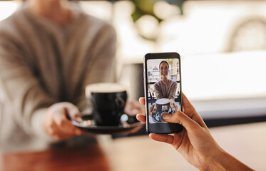 Woman taking pictures of her friend in cafe