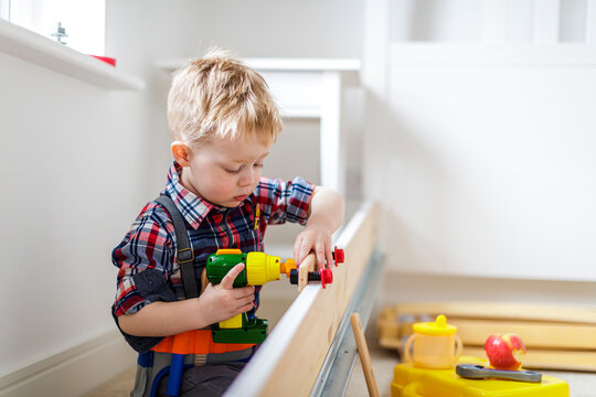 Young boy using toy power tool at home