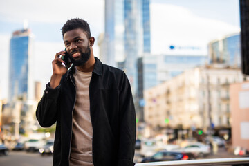 African American man smiling and talking on the phone while walking down the street