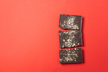 Handmade chocolate bars with berries on a red background. View from above.