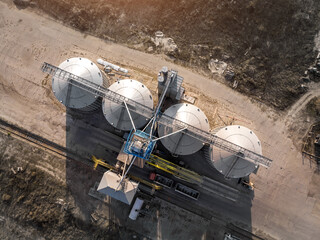Top down view modern steel agricultural grain granary silos cereal storage warehouse loading cargo grain carrier at sunset. Agribuisness farmland rural industry landscape scene. Mill store facility © Kirill Gorlov
