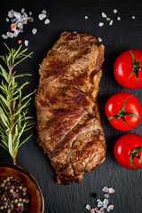  Grilled beef steak with spices on a black background, close up, vertical photo