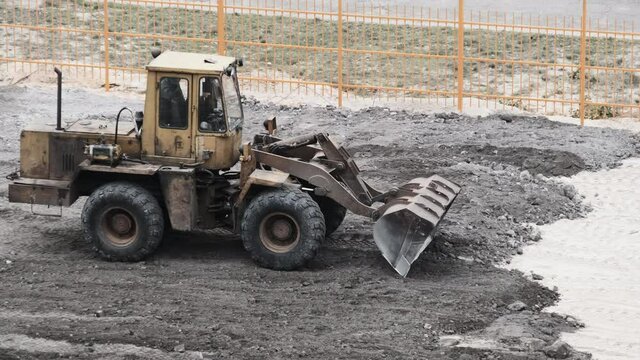 An Old Bulldozer on Rubber Wheels Works on Construction Site.