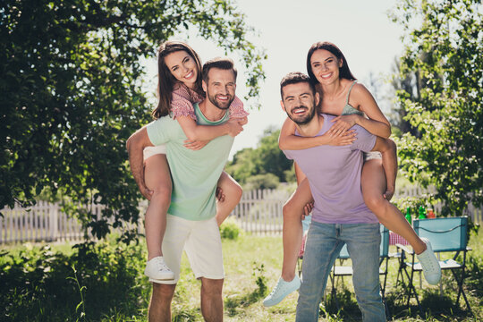 Photo of company four buddies smiling having fun piggyback outside outdoors garden park forest
