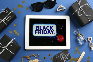 Flat lay composition with tablet, gifts and accessories on blue background. Black Friday sale