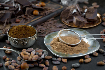 Dark chocolate in a composition with cocoa beans and nuts, on an old background.