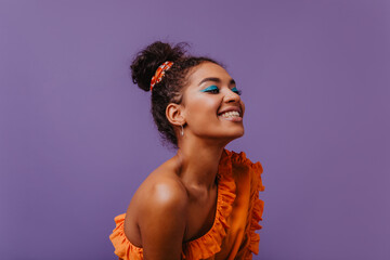 Blissful black woman in summer dress laughing on violet background. Adorable african girl in orange...