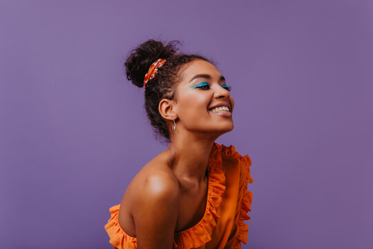 Blissful Black Woman In Summer Dress Laughing On Violet Background. Adorable African Girl In Orange Outfit Posing With Happy Face Expression.