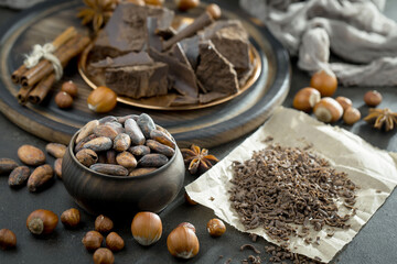 Dark chocolate in a composition with cocoa beans and nuts, on an old background.