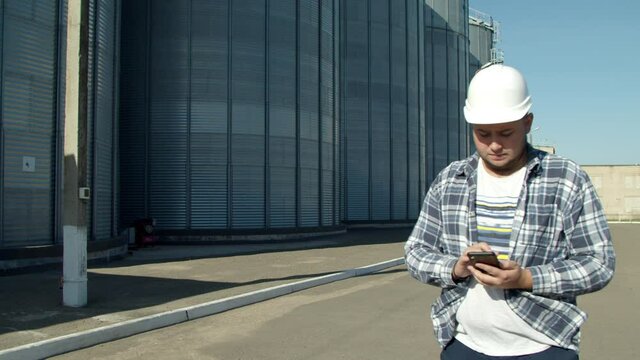 Professional engineer doing calculations near agricultural silos