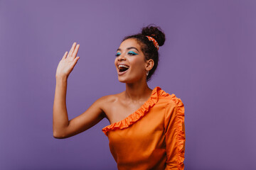 Gorgeous young woman posing with excitement on purple background. Indoor photo of ecstatic african girl.