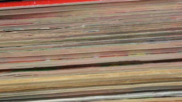 Closeup view 4k video footage of old paper texture of many old stacked magazines.