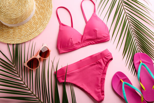Beautiful bikini and beach accessories on pink background, flat lay