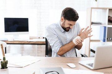 Man suffers and hold on to a sore wrist at work.