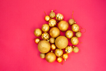 Gold glitter. Christmas balls of different sizes are collected in a bunch on a pink background. Flat lay, top view.