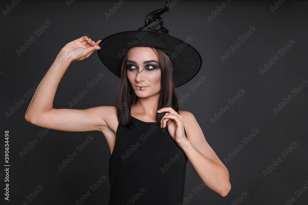 Wall mural Mysterious witch wearing hat on black background