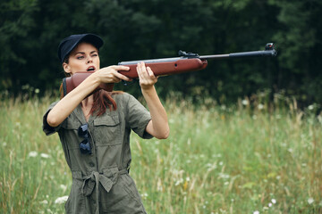 Woman on outdoor a woman holds a gun in front of her aiming at a hunt green leaves green 