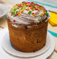 Easter cake with colorful marzipans on a white plate close up on a colored tablecloth