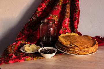 still life with a jar of jam, a plate of pancakes and fresh bananas on a Russian traditional shawl...